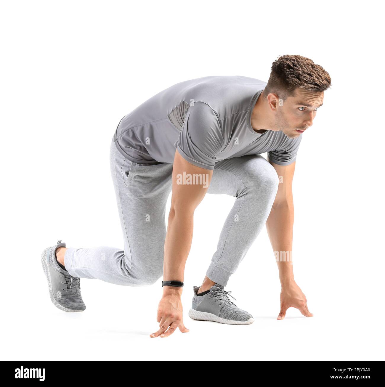 Sportlicher junger Mann in Crouch Startposition auf weißem Hintergrund Stockfoto