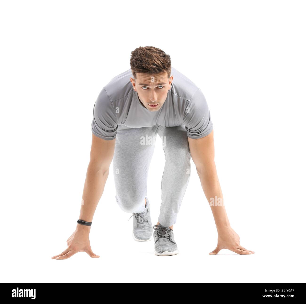 Sportlicher junger Mann in Crouch Startposition auf weißem Hintergrund Stockfoto