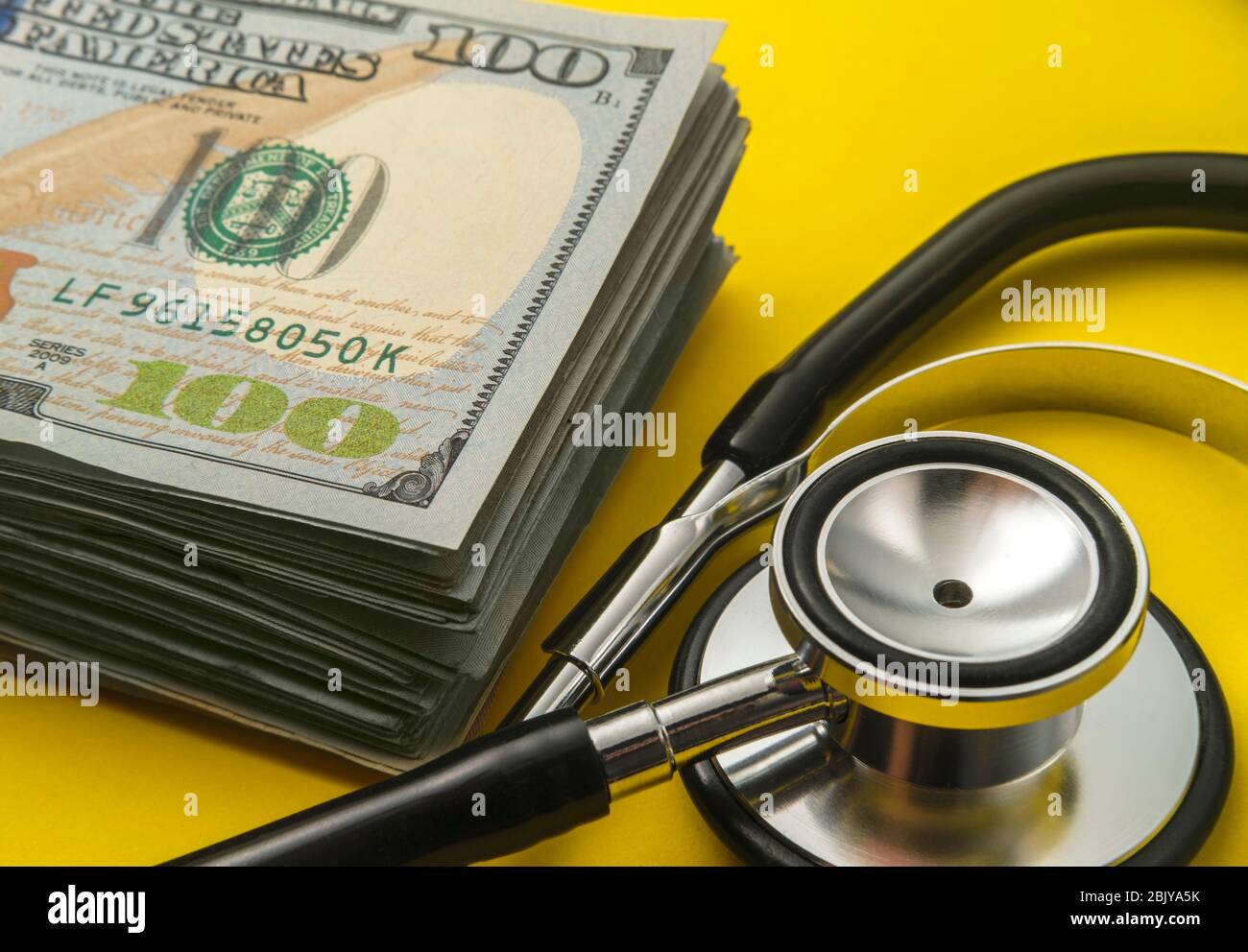 Stapel von 100 Dollar Scheine und stethoscopeÂ auf gelb backgroundÂ Stockfoto