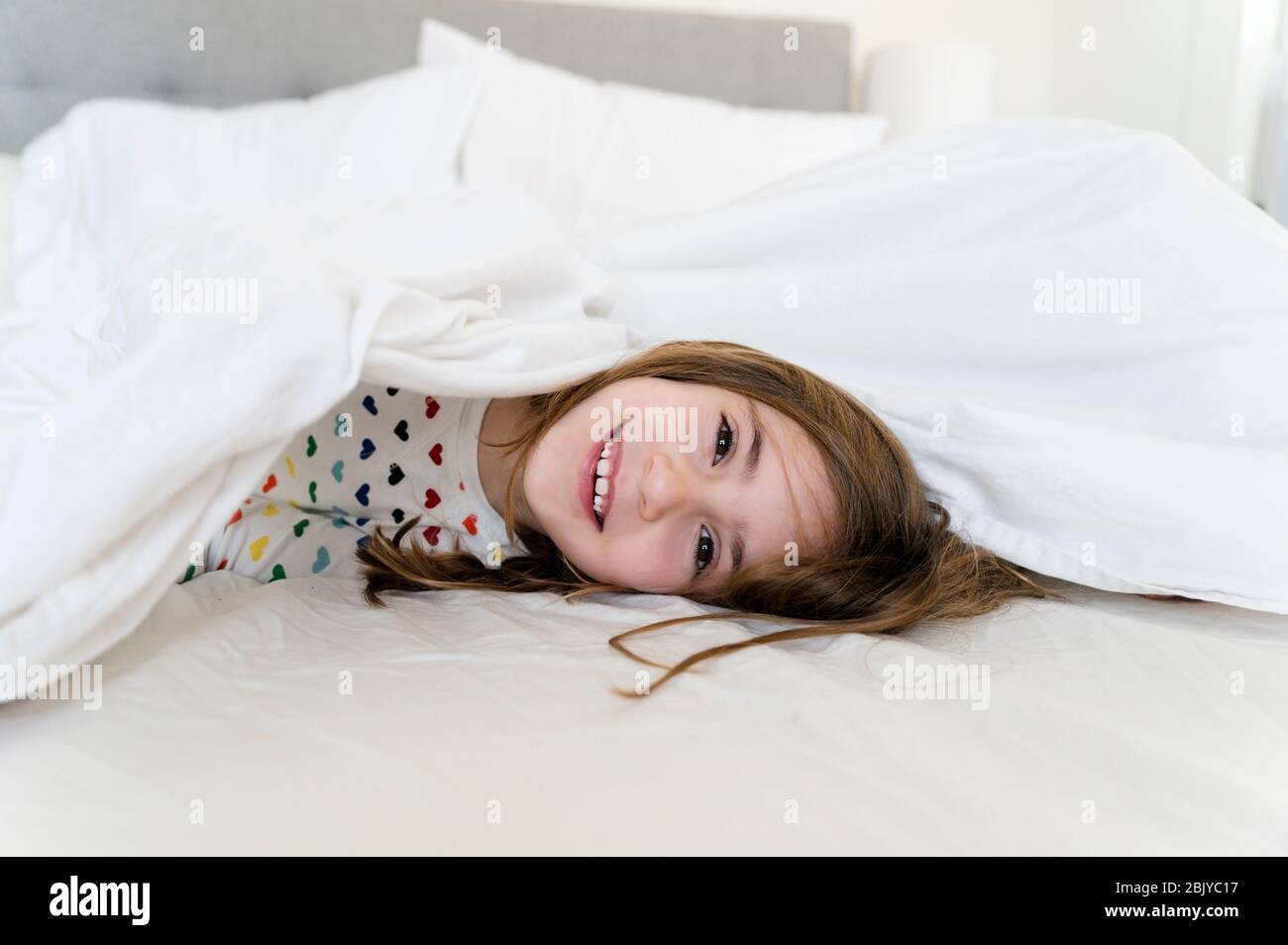 Kleines Mädchen liegt im Bett smilingÂ Stockfoto