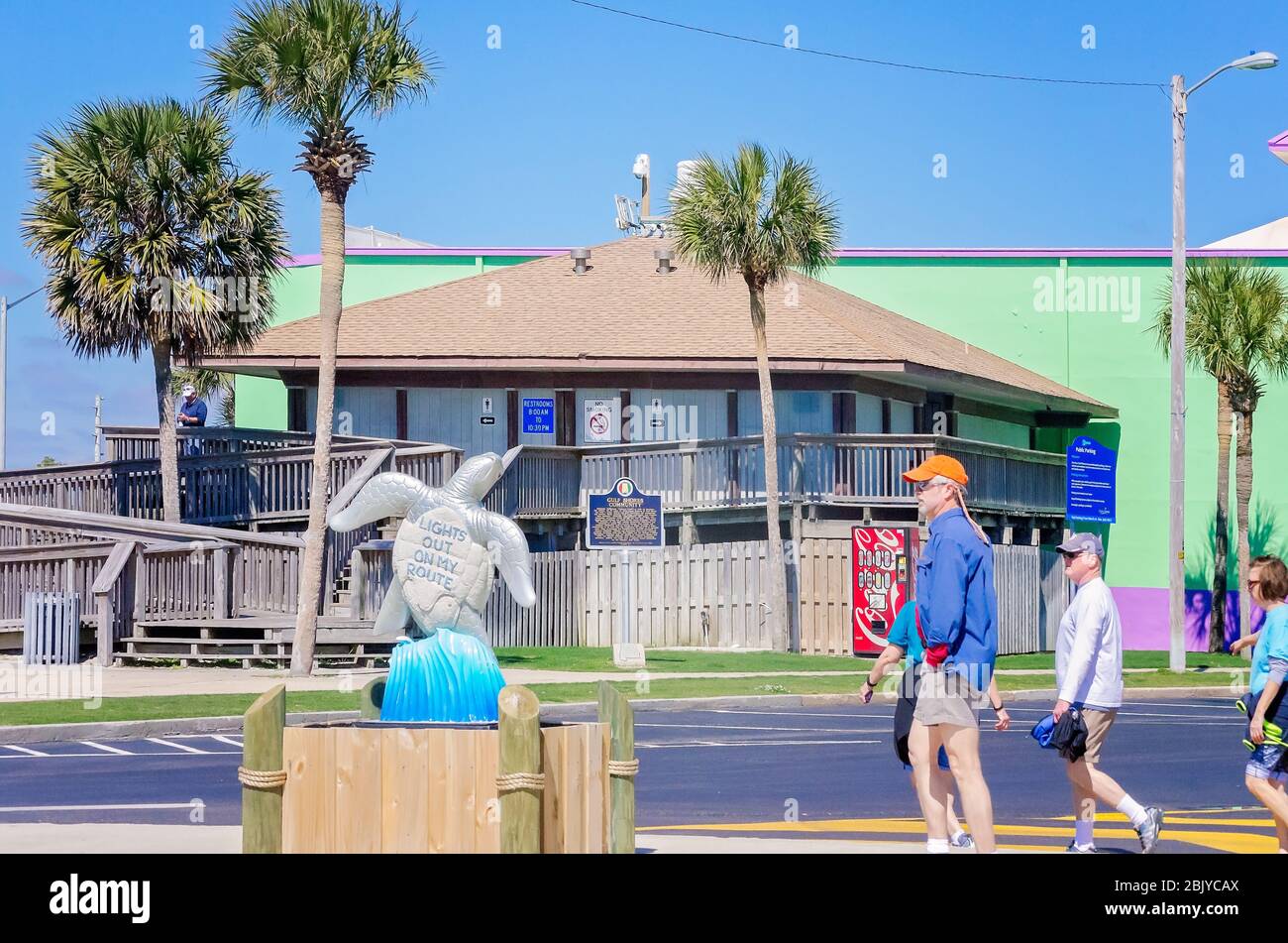 Touristen gehen an einer Schildkrötenskulptur vorbei, die in der Innenstadt in der Nähe des Strandes steht, als Teil eines öffentlichen Kunstprojekts, 4. März 2016, in Gulf Shores, Alabama. Stockfoto