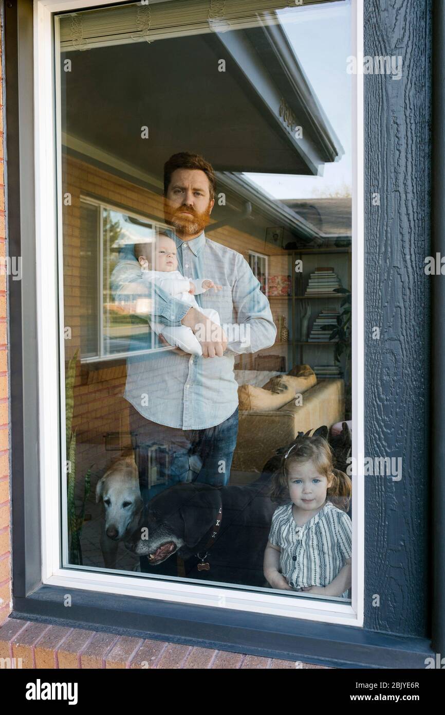 Vater mit Kindern (2-5 Monate, 2-3) schaut durch das Fenster Stockfoto