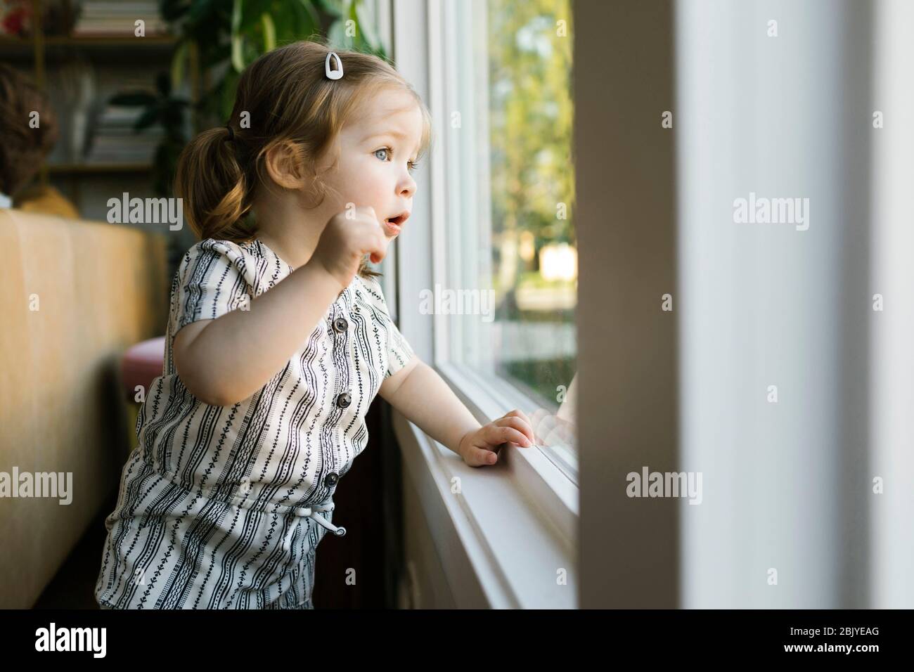 Mädchen (2-3) schaut durch das Fenster Stockfoto