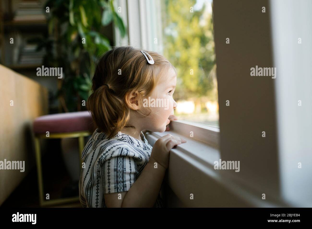 Mädchen (2-3) schaut durch das Fenster Stockfoto