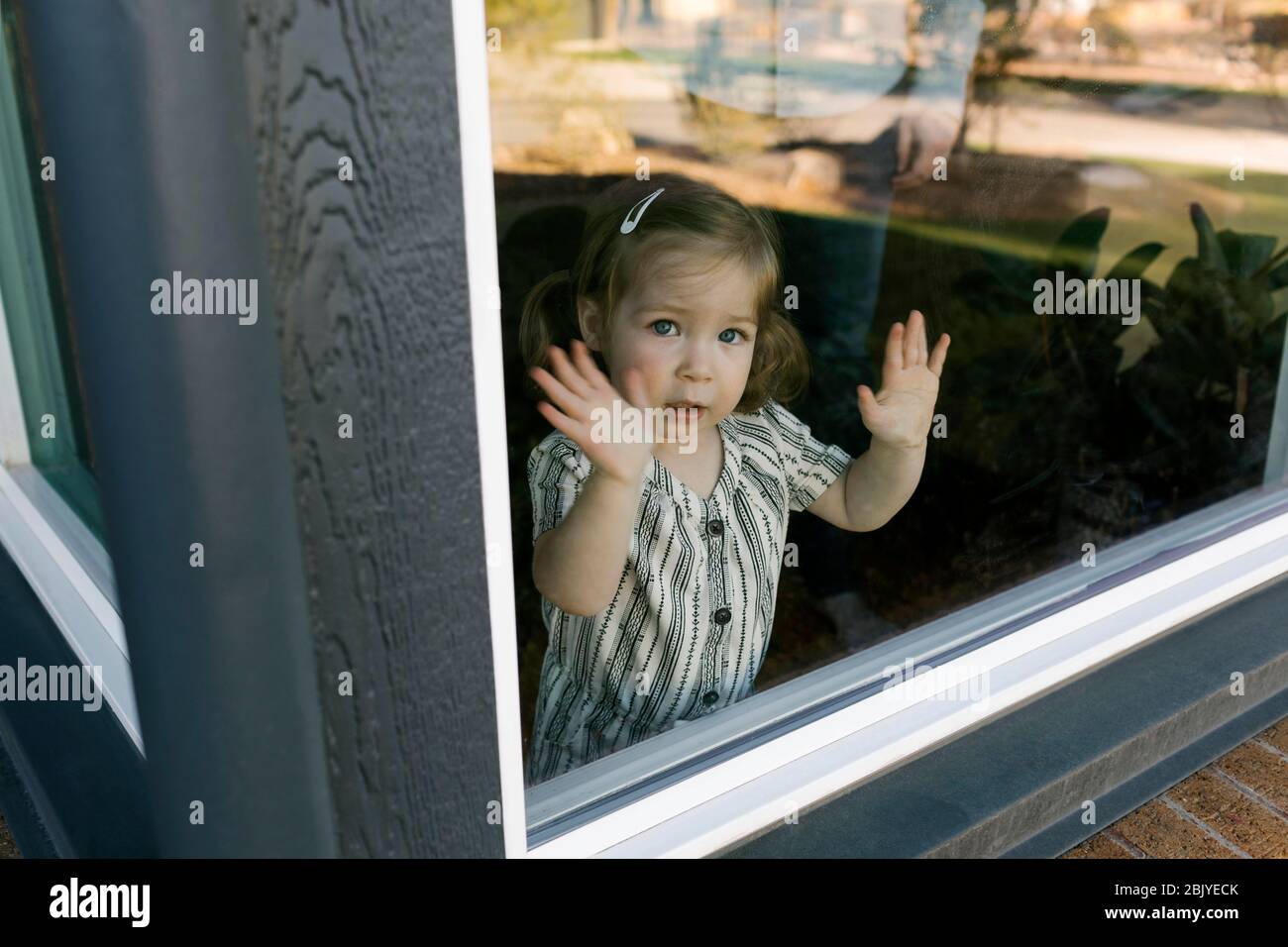 girlâ (2-3)Â Blick durch das Fenster Stockfoto