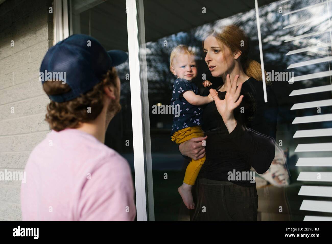 Mutter mit Tochter (2-3) im Gespräch mit dem Mann durch das Fenster Stockfoto