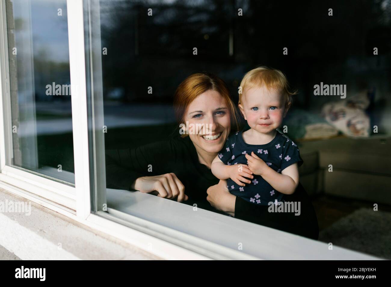Mutter und Tochter (2-3) blicken durch das Fenster Stockfoto