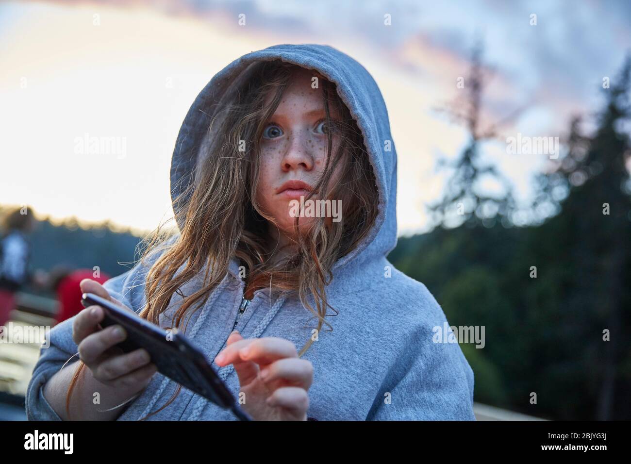 Mädchen im Hoodie mit Telefon Stockfoto