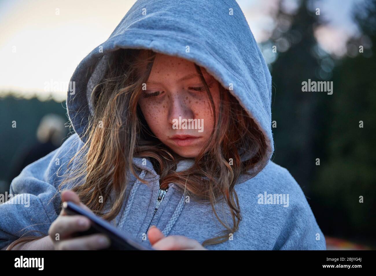 Mädchen im Hoodie mit Telefon Stockfoto