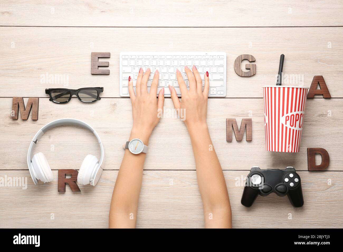 Weibliche Hände mit Computer Tastatur, Joypad, Kopfhörer und Buchstaben auf Holz- Hintergrund Stockfoto