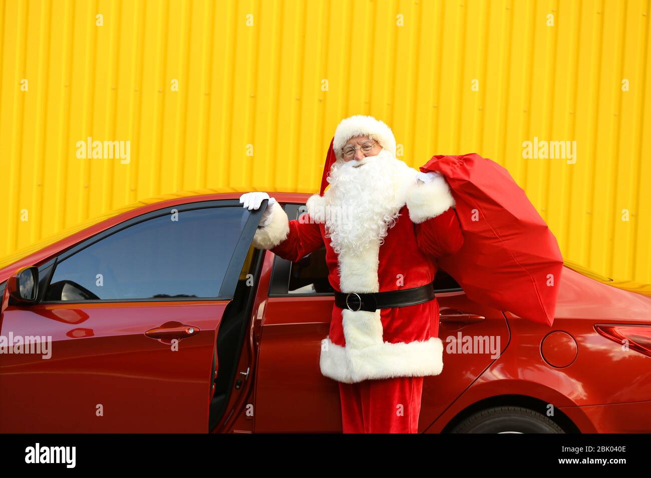 Weihnachtsmann mit Geschenken im Beutel in der Nähe Auto im Freien Stockfoto