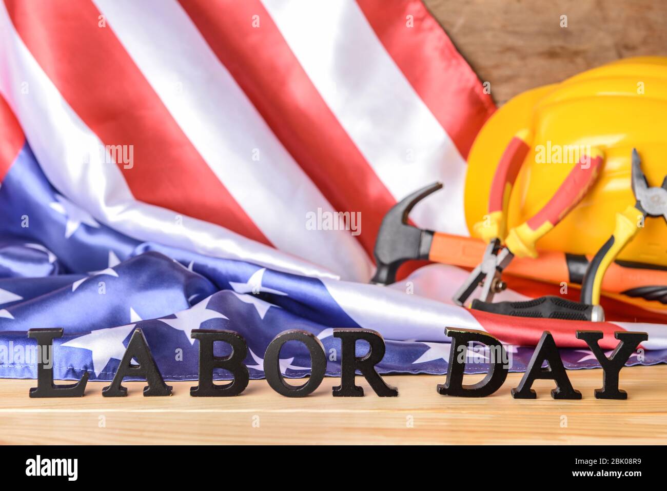 USA-Flagge, hardhat, Werkzeuge und Text TAG DER ARBEIT auf hölzernen Tisch Stockfoto