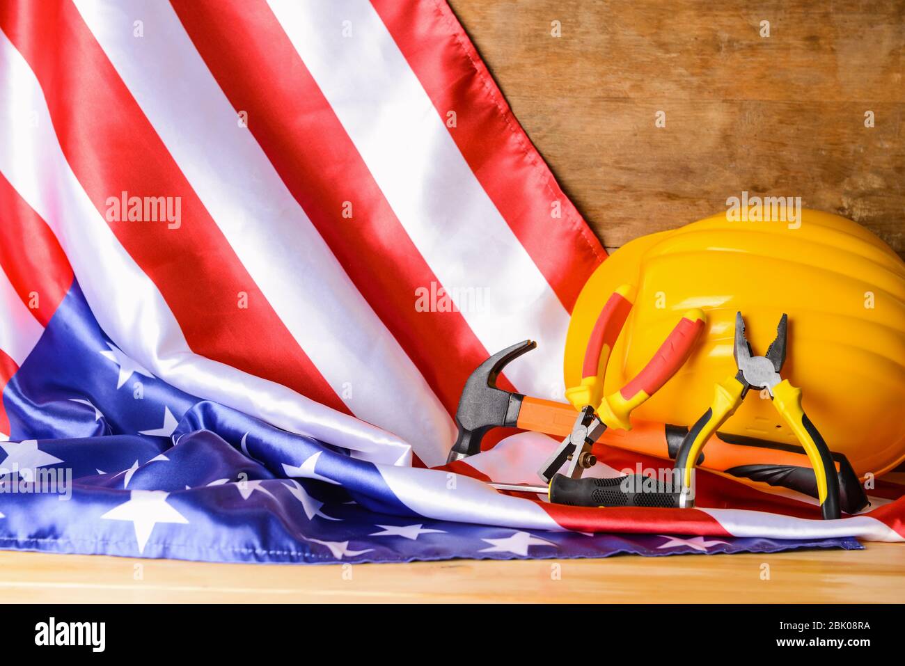 USA-Flagge, hardhat und Tools auf Holztisch. Feier zum Tag der Arbeit Stockfoto