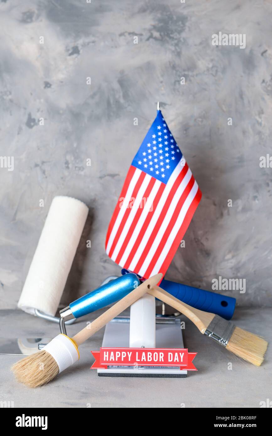 USA-Flagge, Werkzeuge und Text HAPPY TAG DER ARBEIT auf die Graue Tabelle Stockfoto