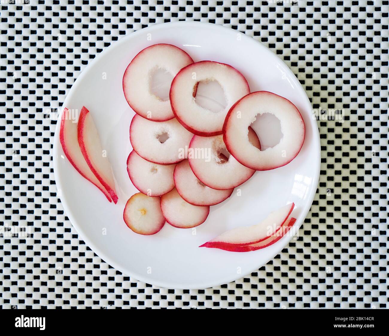 Scheiben Rosenobst in einem Teller auf einer weißen Oberfläche Stockfoto