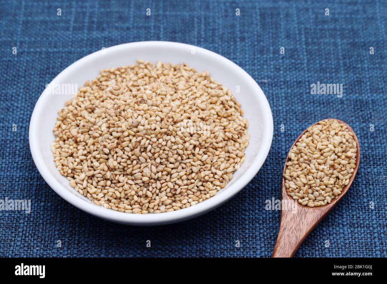 Weiße Sesamsamen in einer Schüssel mit Holzlöffel auf dem Tisch Stockfoto