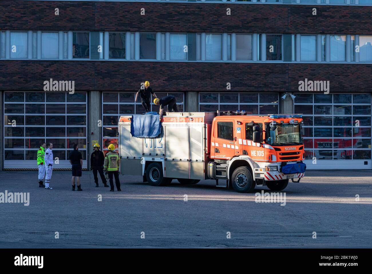 Feuerwehrleute üben vor Kallio Feuerfest. Abendsonne leuchtet die Feuerlöschmaschine. Helsinki, Finnland. Stockfoto