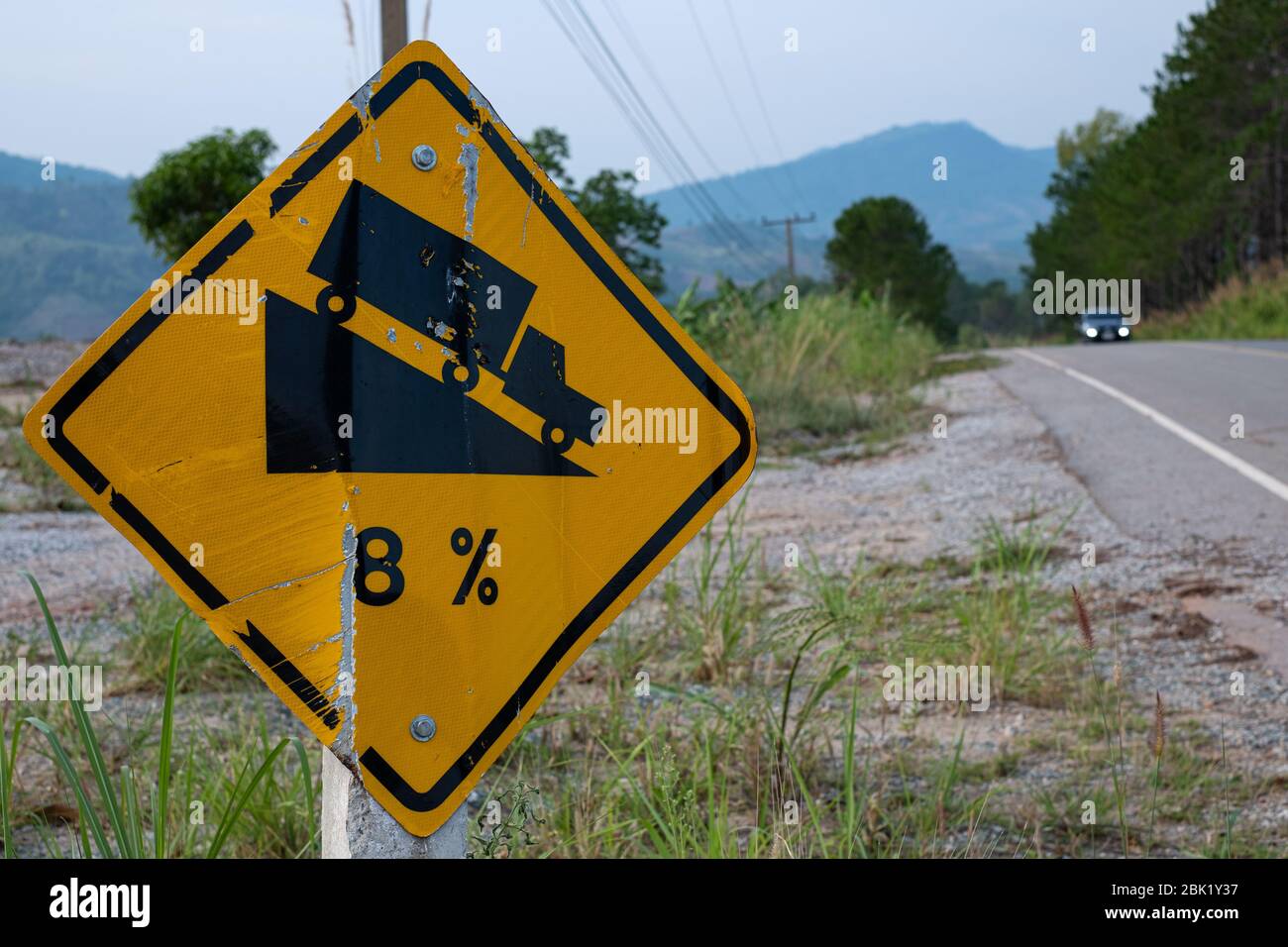 Verkehrszeichen Warnung steile Straßenschild zum Hang eine steile 8 Prozent Steigung bergab in der Straße voraus bei grünem Gras im Hintergrund Stockfoto