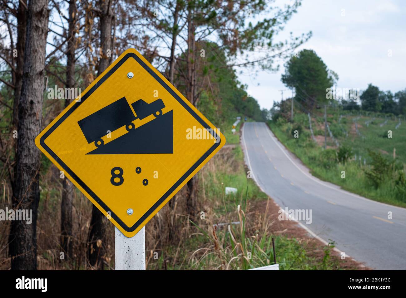 Verkehrszeichen Warnung bis zu Hügel steile Straßenschild zu Hang eine steile Steigung 8 Prozent Steigung in der Straße voraus bei grünem Gras im Backgroun Stockfoto