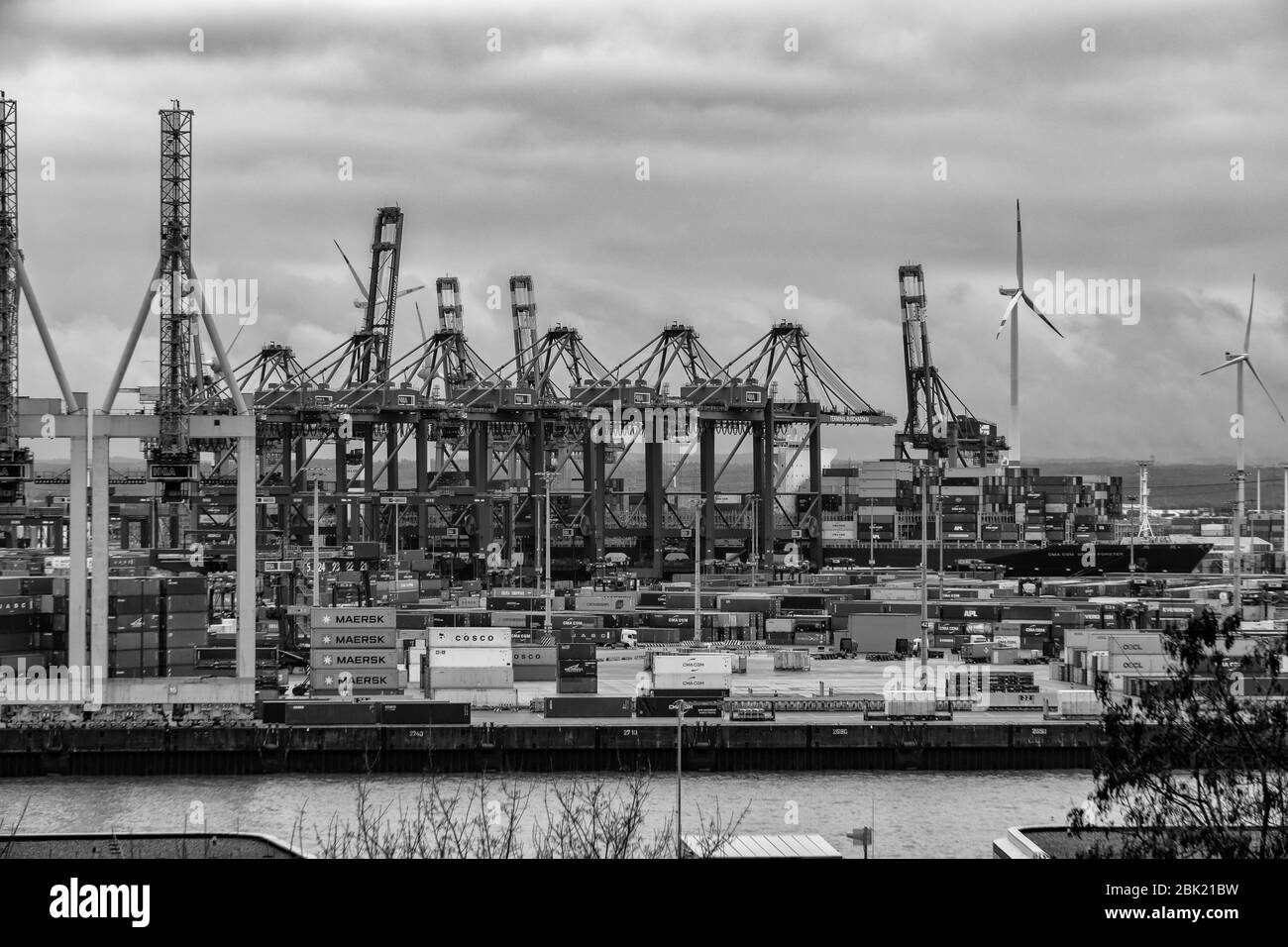 Hamburger Containerhafen mit einigen Schiffen, die Container zu den Frachtern mit dramatischem Himmel/Wolken transportieren, Deutschland Stockfoto