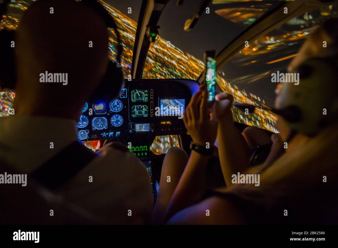Sehen Sie sich Piloten und Kunden an, die Handyfotos bei einem Hubschrauberflug über Vegas bei Nacht, Las Vegas, Nevada, USA, Nordamerika machen Stockfoto