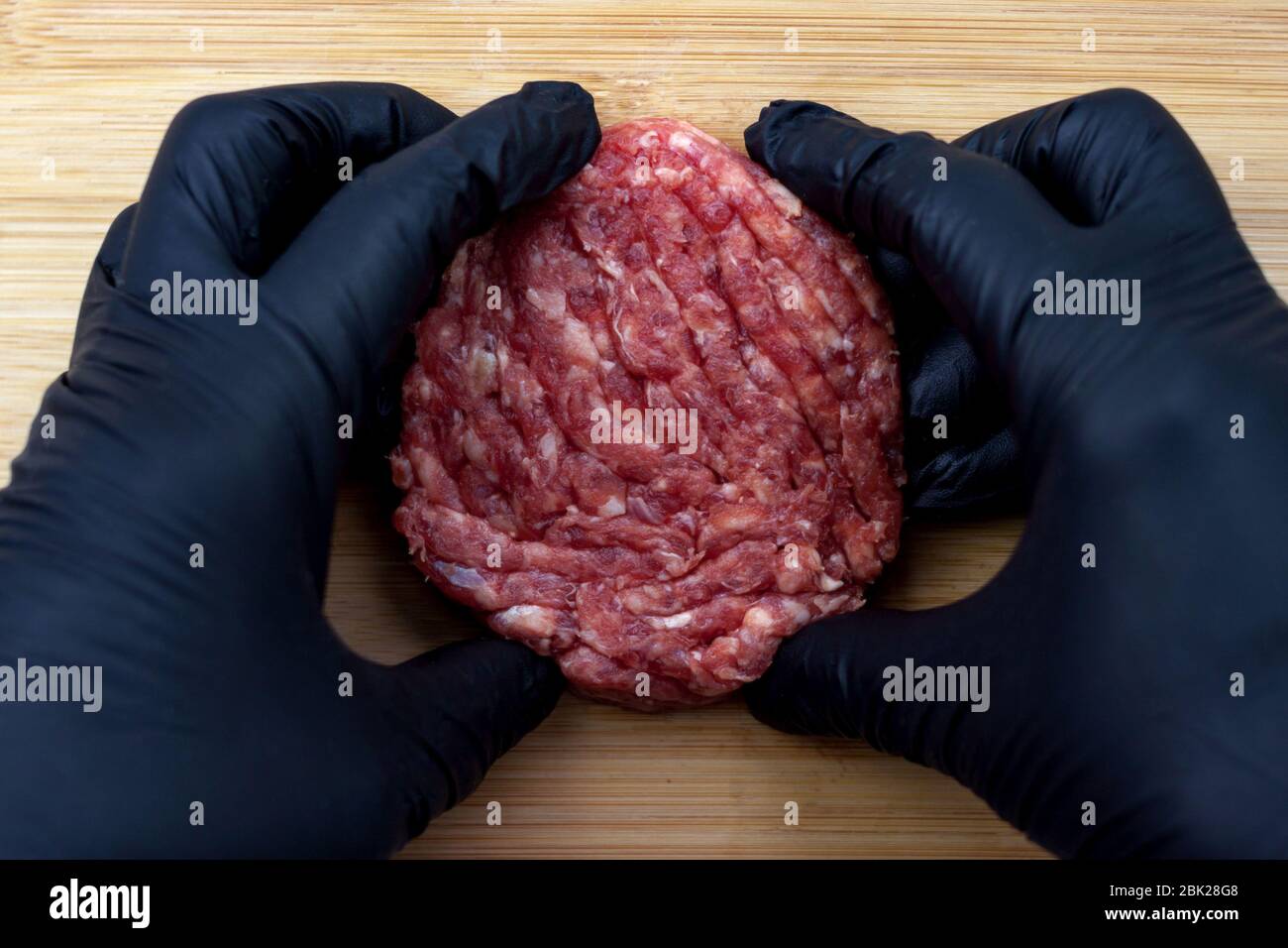 Rohes Rindfleisch Burger Kochen auf natürlichen Bambus Holz Schneidebrett Hintergrund close-up. Draufsicht. Stockfoto