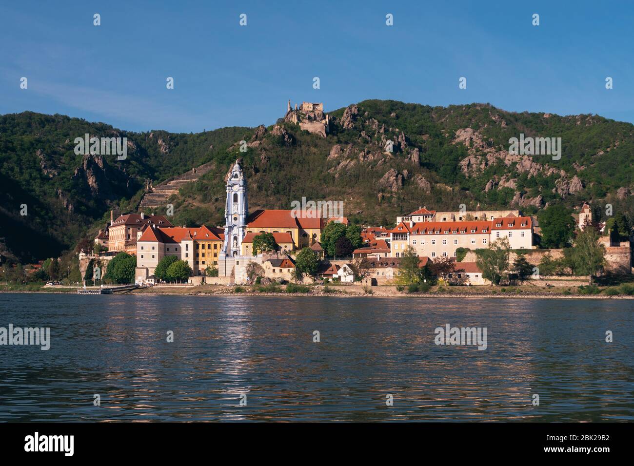 Stadtbild von Dünstein mit dem blau-weißen barocken Klosterkirche-Turm und dem Schloss Kuenringer an der Donau in der Wachau, Österreich Stockfoto