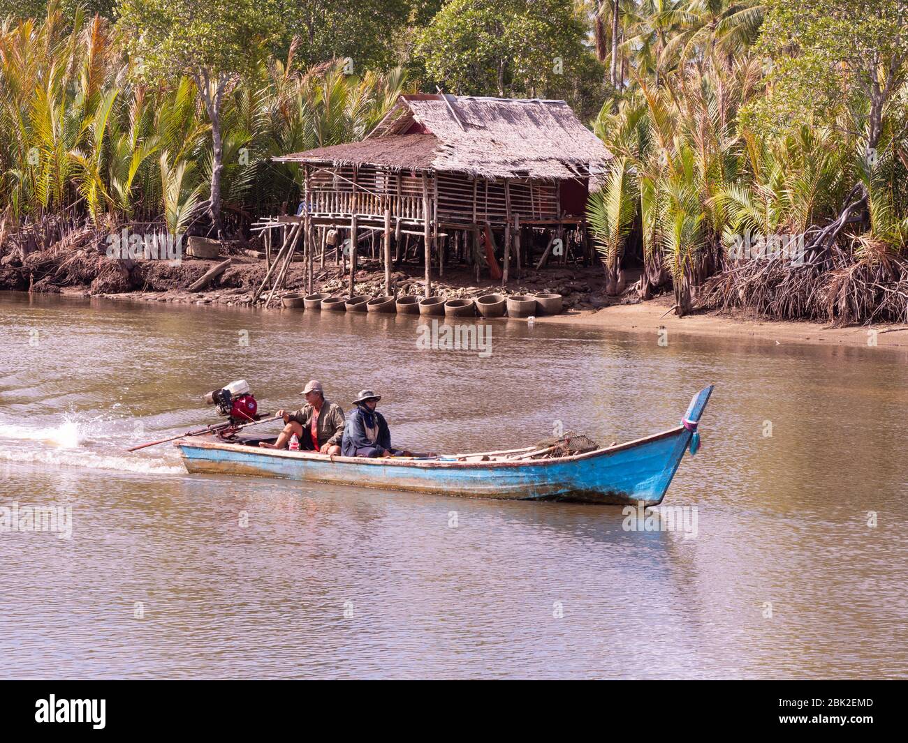 Kleines Langschwanzboot auf Mak Bang, Satun City, Satun im Süden Thailands. Traditionelles Haus auf Stelzen im Hintergrund. Stockfoto Kleines Langschwanzboot auf Mak Bang, Satun City, Satun im Süden Thailands. Traditionelles Haus auf Stelzen im Hintergrund. Stockfoto