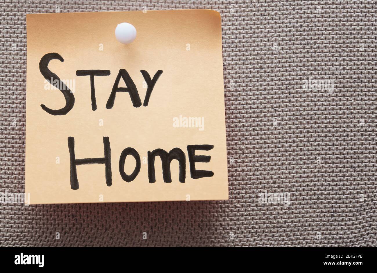 Haftnotiz mit Stay Home-Text auf einem Pinnwand Stockfoto