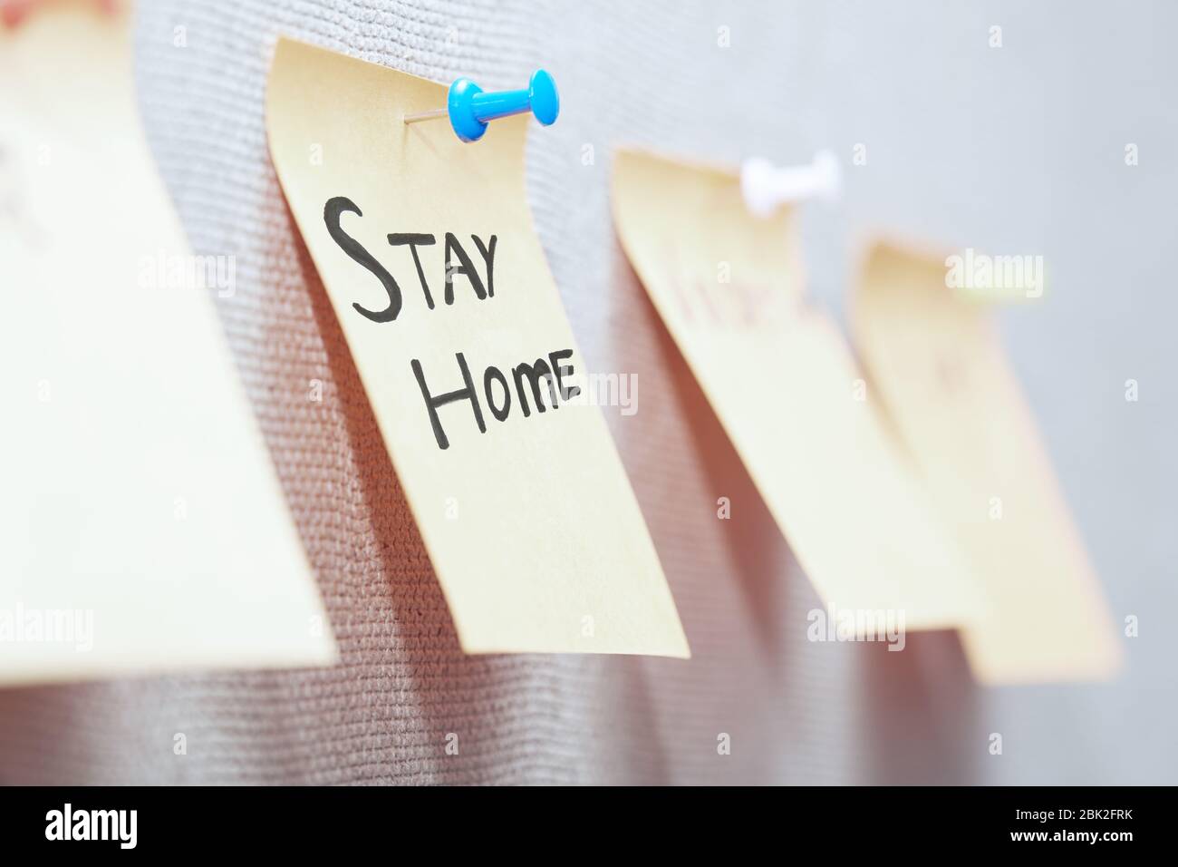 Haftnotiz mit Stay Home-Text auf einem Pinnwand Stockfoto