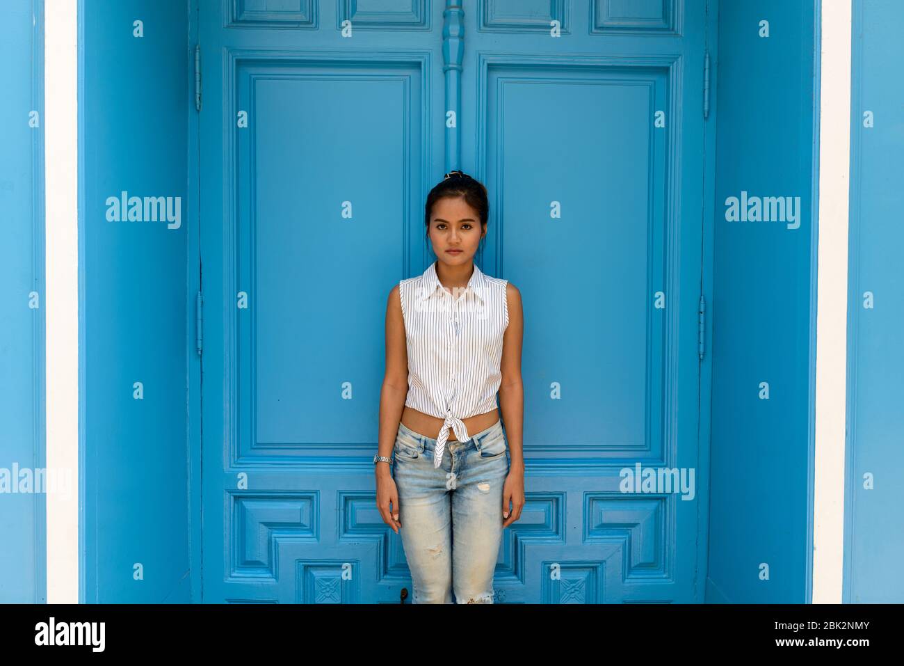 Junge schöne asiatische Frau vor der blauen Tür stehen Stockfoto