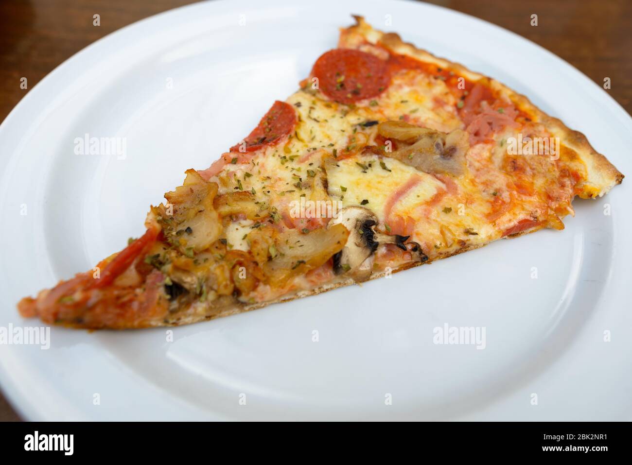 Eine Scheibe köstliche dünne knusprig gepfirschte Pfefferoni-Pilzpizza Stockfoto