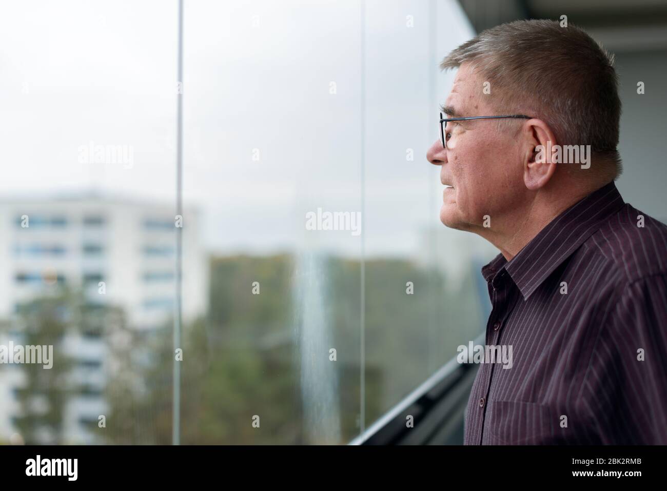 Profilansicht des alten Mannes denken, während Blick aus Glasfenster des modernen Gebäudes Stockfoto