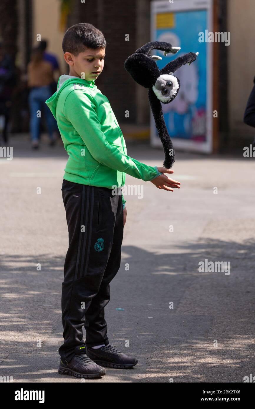 Profilporträt eines Jungen, der einen weichen Spielzeugaffen im Londoner Zoo schwingt Stockfoto