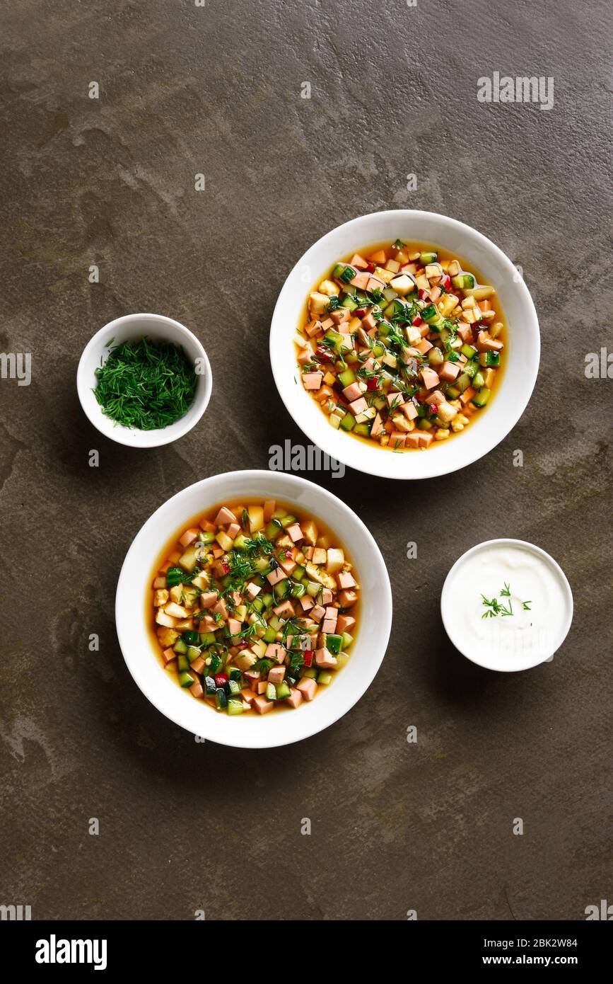 Traditionelle kalte russische Suppe Okroschka mit Wurst, Gemüse und Kvass über braunem Hintergrund. Leckeres Sommergericht zum Abendessen. Draufsicht, flacher Lay Stockfoto