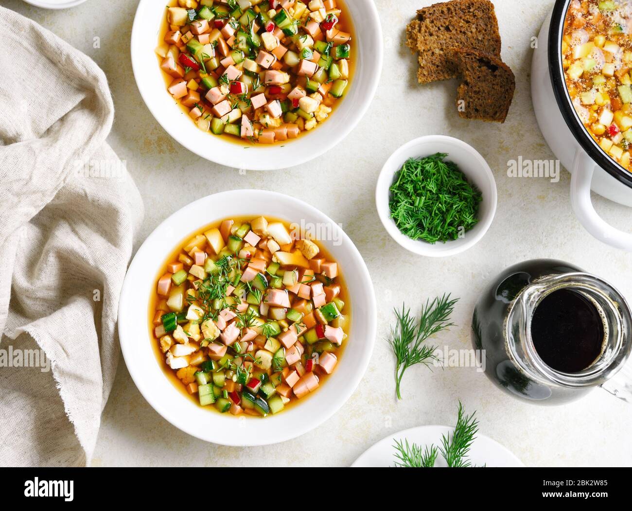Traditionelle kalte russische Suppe Okroschka mit Wurst, Gemüse und Kvass über hellem Steinhintergrund. Draufsicht, flacher Lay Stockfoto