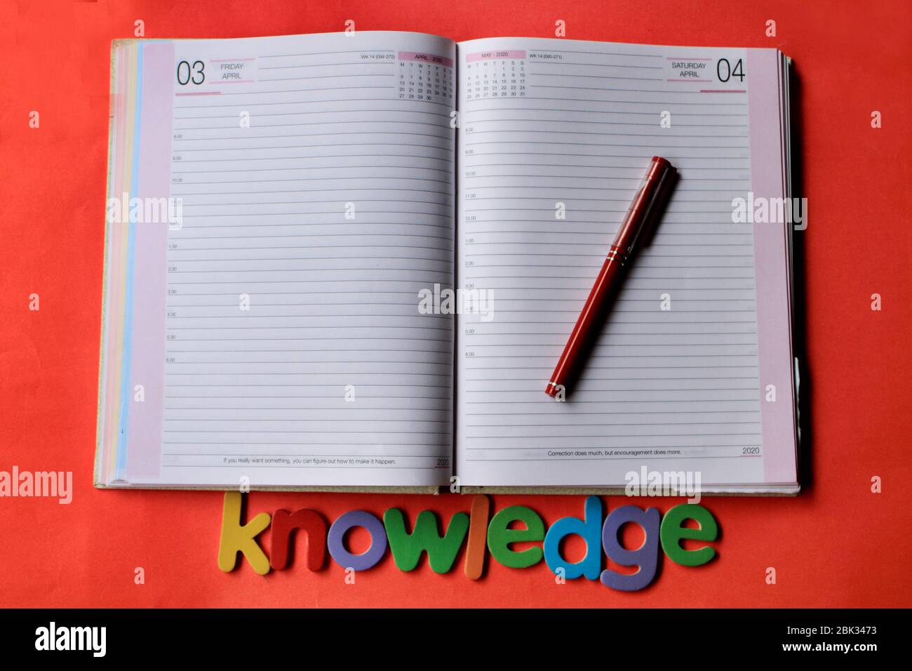 Das Wort Wissen auf rotem Hintergrund mit Tagebuch Seite und Stift geschrieben. Stockfoto
