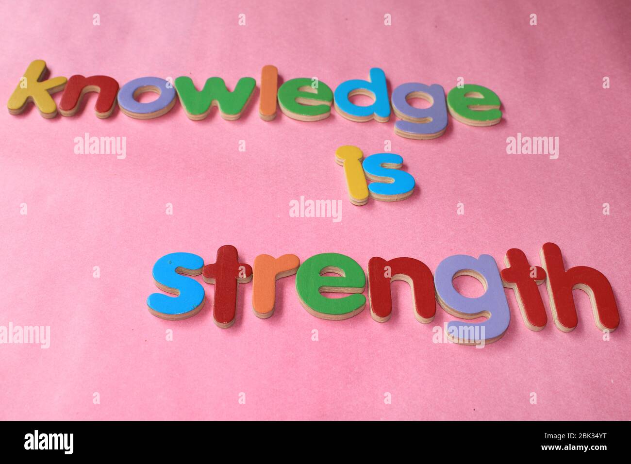 Wissen ist Stärke. Wissen ist Kraft, die mit dem englischen Holzalphabet an die Wand geschrieben wird. Stockfoto