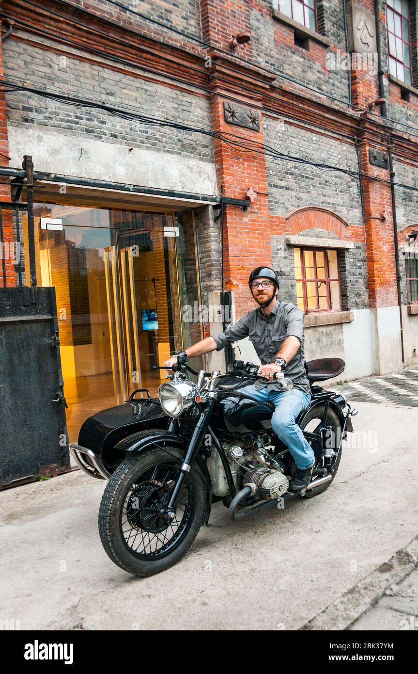 Shanghai Insider Arthur Humeau auf seinem Changjiang 750 Motorrad seitenwagen vor ArtCN, in der ehemaligen Foh singen Mühle Gebäude in Shanghai ins Stockfoto