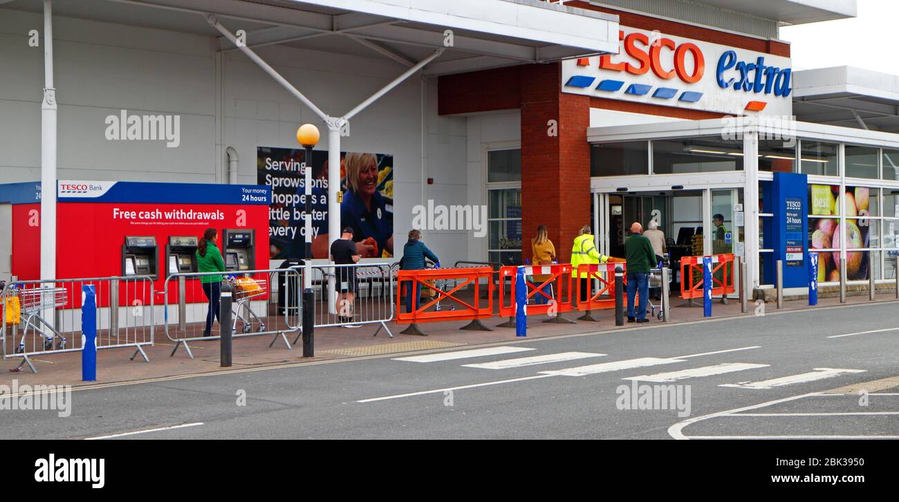 Eine Schlange von Käufern, die soziale Distanz respektieren und darauf warten, in einen Tesco Extra Supermarkt in Sprowston, Norfolk, England, Vereinigtes Königreich zu gehen. Stockfoto