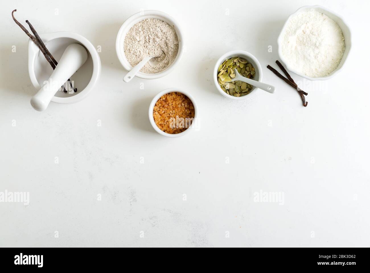 Zutaten zum Backen von selbstgemachtem frischem Brot oder leckeren Kuchen - Mehl, Weizen und Roggen, Rohrzucker, Kürbiskerne auf hellgrauem Marmorgrund, Polizist Stockfoto