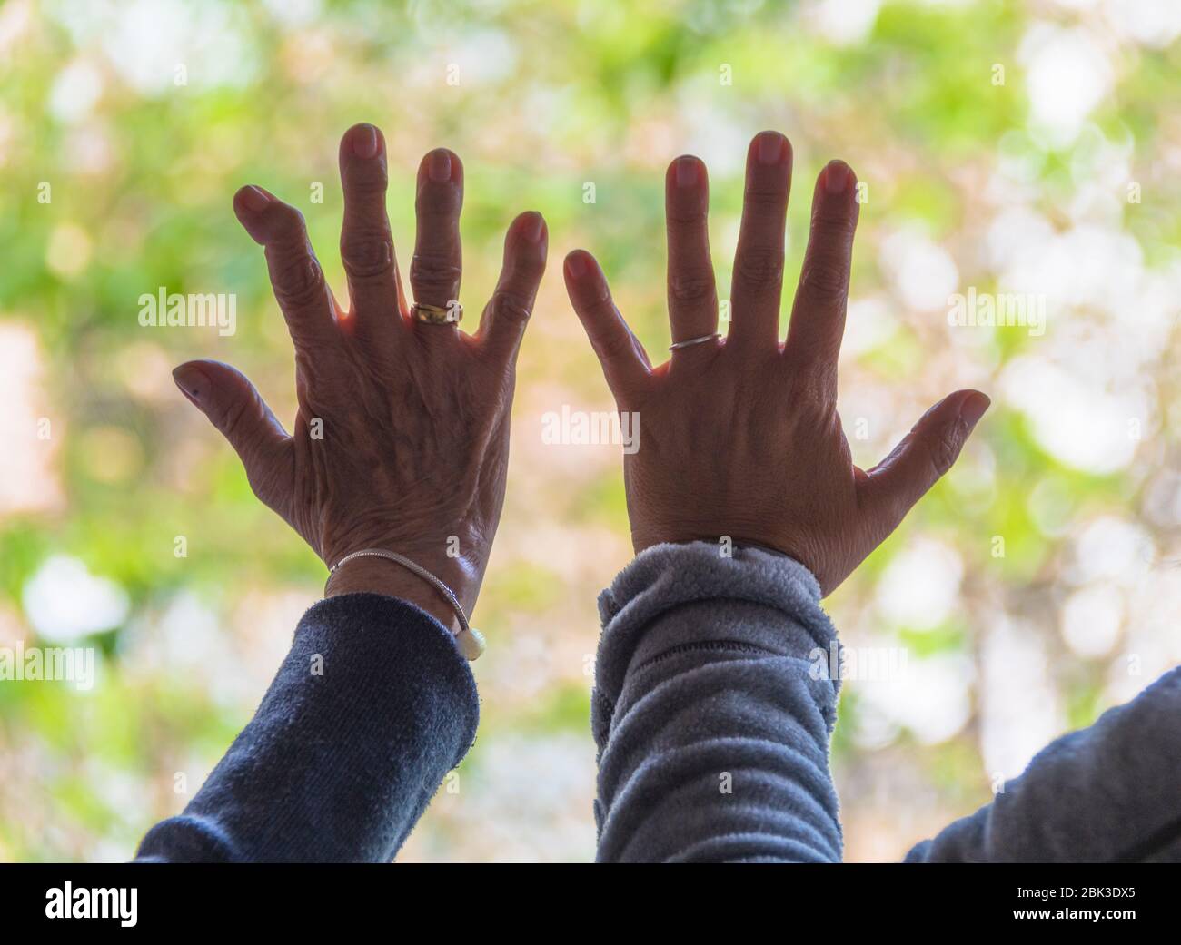 Frauen in Gefangenschaft mit Händen auf Fensterscheibe, Blick auf die Straße Stockfoto