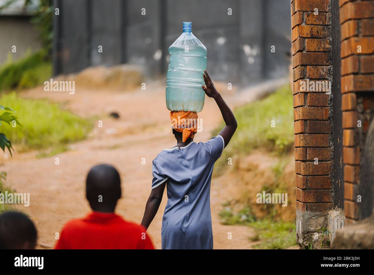 Frau, die Wasser in Entebbe, Uganda, trägt Stockfoto