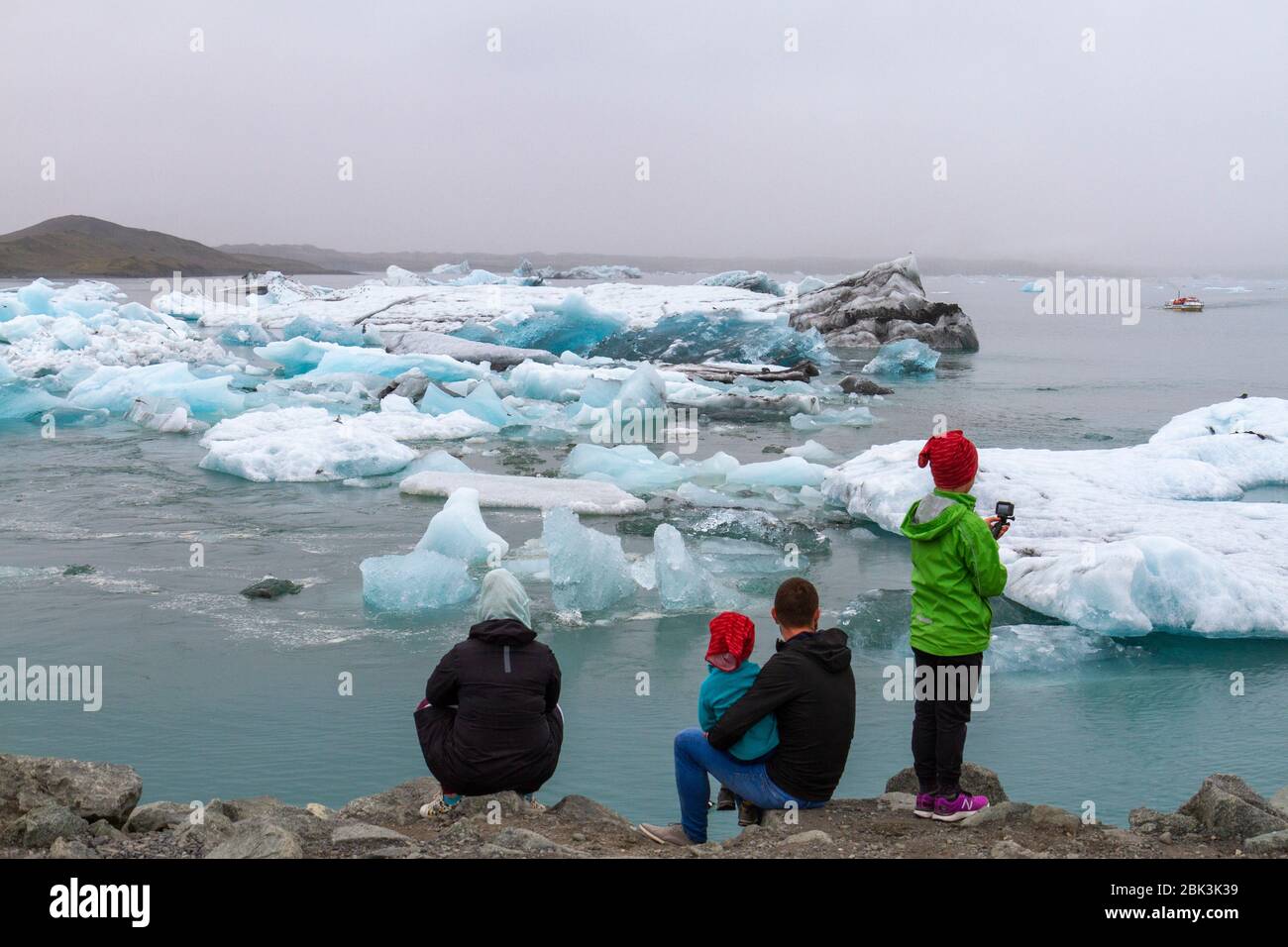 Eine kleine Gruppe von Besuchern (eine Familie), die die Eisberge auf der schönen Jokulsarlon Lagune im Süden Islands betrachten. Stockfoto