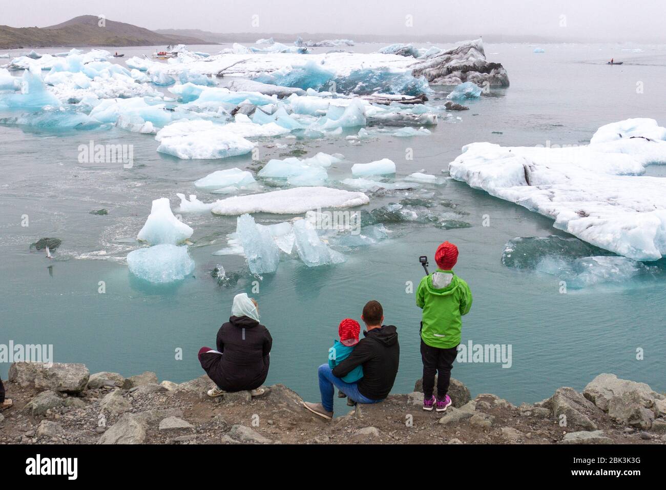 Eine kleine Gruppe von Besuchern (eine Familie), die die Eisberge auf der schönen Jokulsarlon Lagune im Süden Islands betrachten. Stockfoto