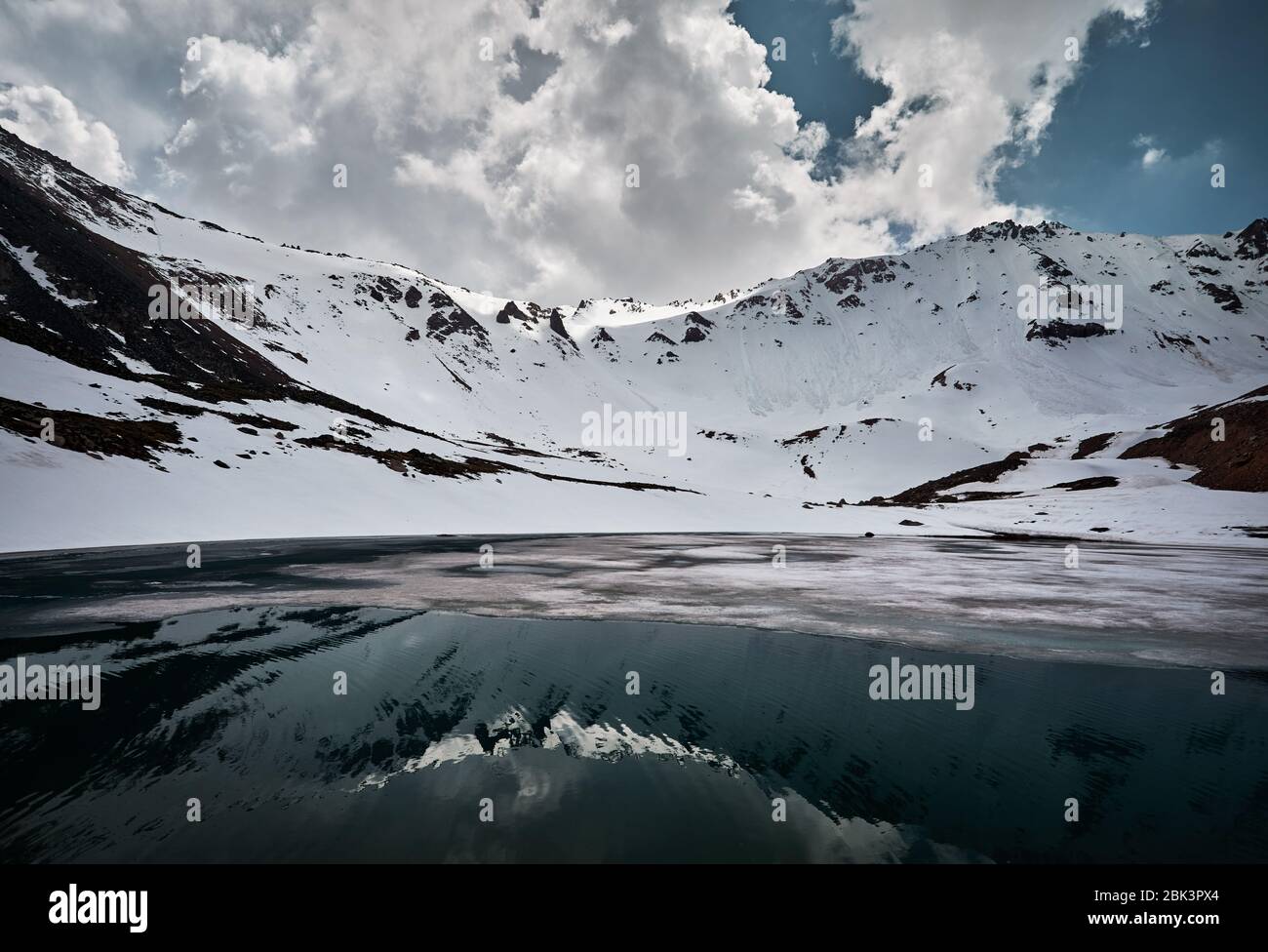 Landschaft aus Schnee Berge und See mit Eis und Reflexion gegen bewölkten Himmel in Kasachstan Stockfoto
