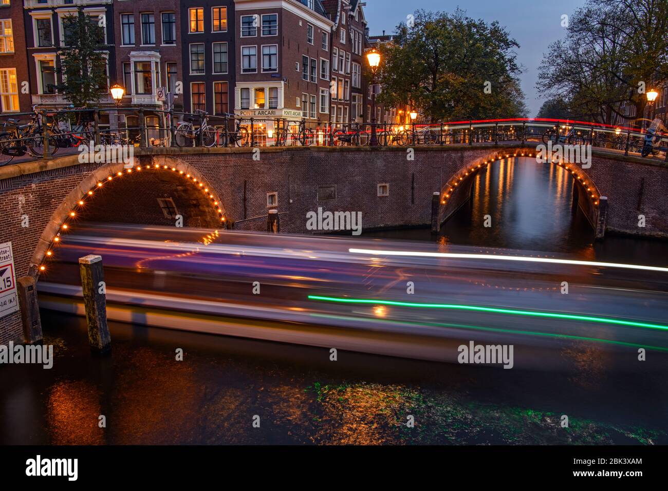 Reflektionen der Brückenbeleuchtung in Kanälen in der Dämmerung, Amsterdam, Nordholland, Niederlande Stockfoto