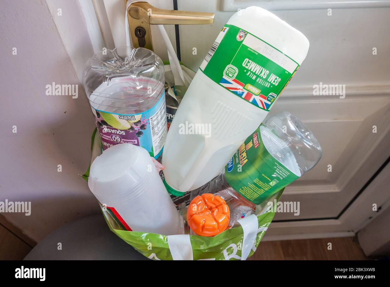 Plastikbeutel für den Supermarkt hing an einem Griff in der Küchentür, der Recyclingabfälle enthielt, die von anderem Hausmüll getrennt wurden. Stockfoto