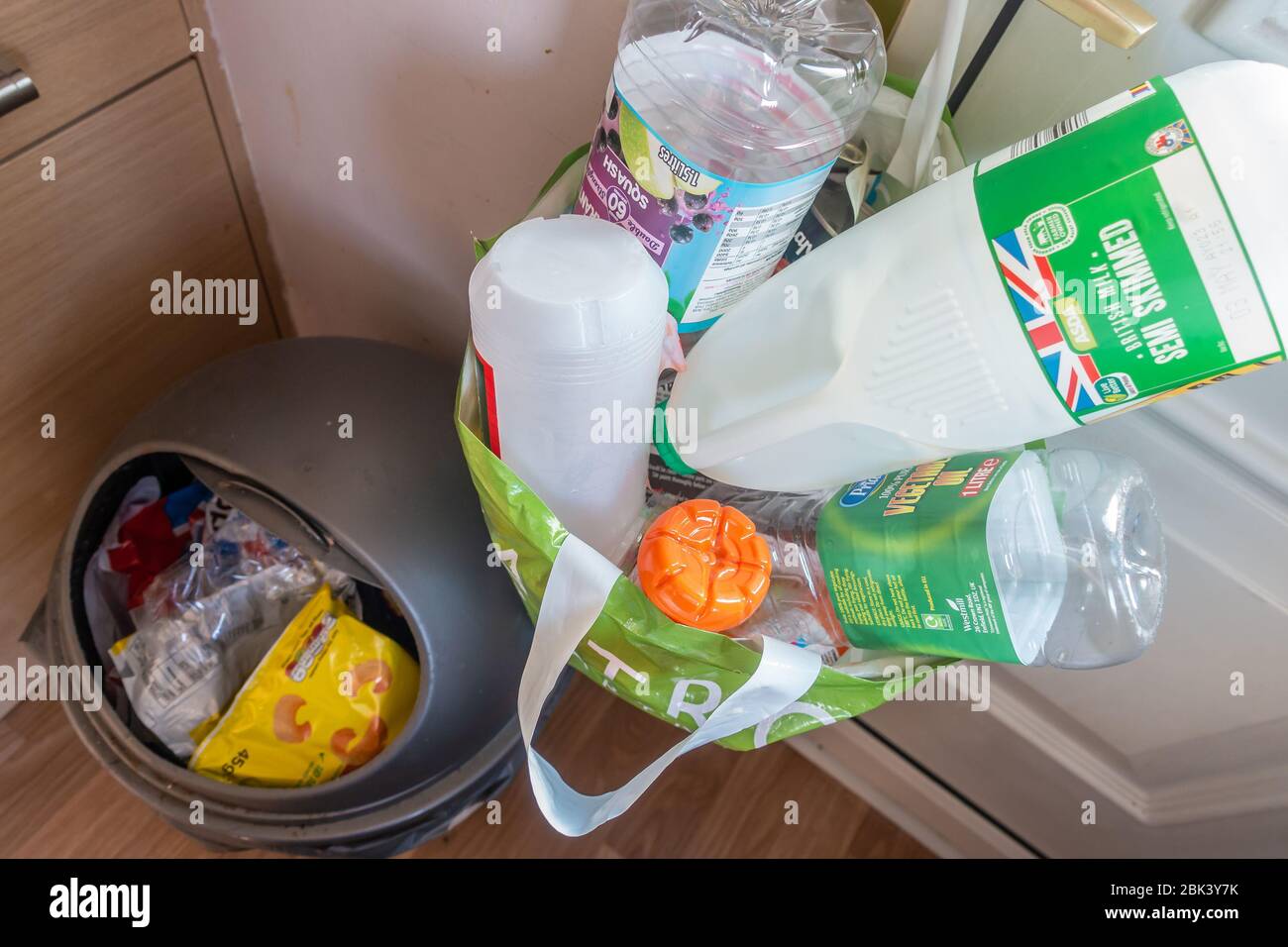 Küchenbehälter für allgemeinen Abfall und Abfall und ein Plastiktragebeutel hing an einem Türgriff für das Recycling von Abfall, der getrennt wurde Stockfoto