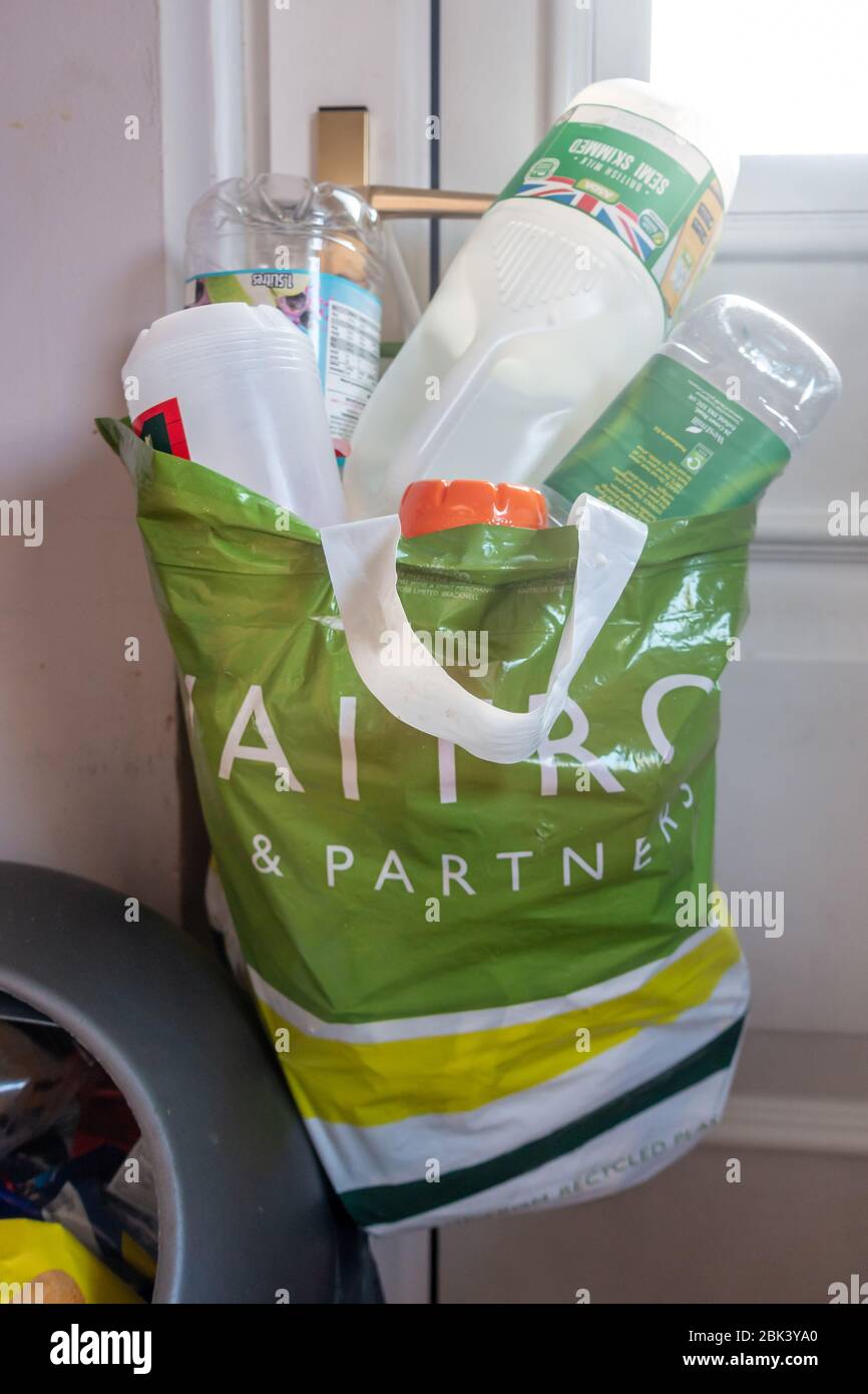 Plastikbeutel für den Supermarkt hing an einem Griff in der Küchentür, der Recyclingabfälle enthielt, die von anderem Hausmüll getrennt wurden. Stockfoto